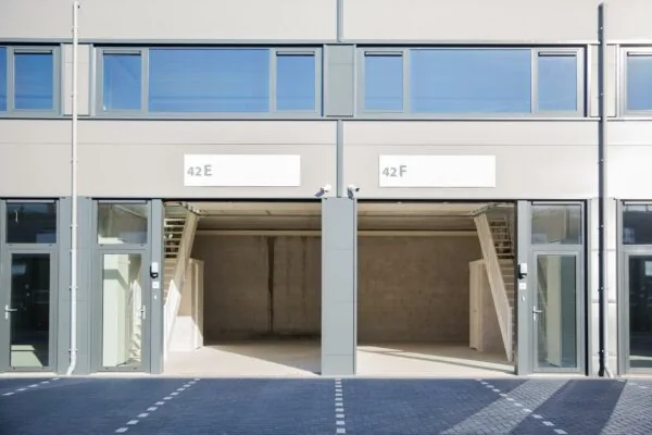 Twee lege bedrijfsunits op Laan van s-Gravenmade, genummerd 42E en 42F, met brede openingen en glazen toegangsdeuren.